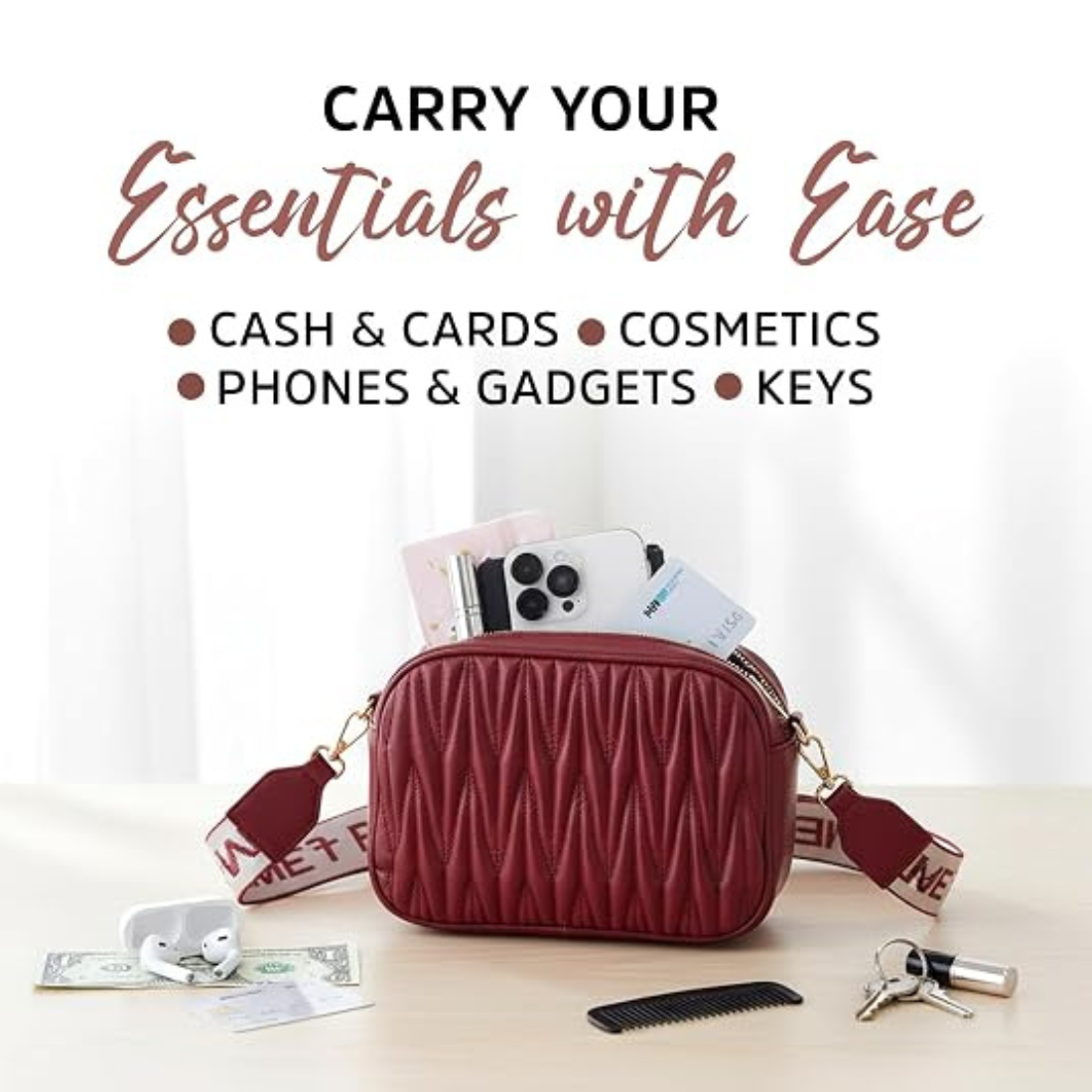 A burgundy quilted crossbody bag with a patterned strap, shown filled with phones, cards, and accessories on a light tabletop. Text above reads 'CARRY YOUR Essentials with Ease' and lists cash, cards, cosmetics, phones, gadgets, keys.