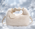A cream-colored faux fur shoulder bag with a matching fabric handle, gold chain strap, and a round leather brand tag that reads 'YON'. The bag is styled in a snowy outdoor setting with soft, icy bokeh background.